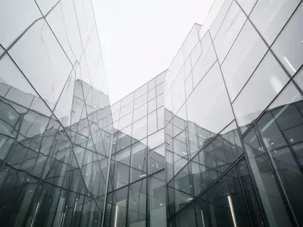 Moderne Glas- und Stahlfassade eines Gebäudes unter einem bewölkten Himmel. - Foto: über boerse-global.de