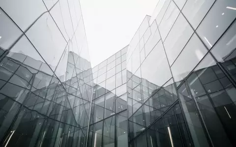 Moderne Glas- und Stahlfassade eines Gebäudes unter einem bewölkten Himmel. - Foto: über boerse-global.de
