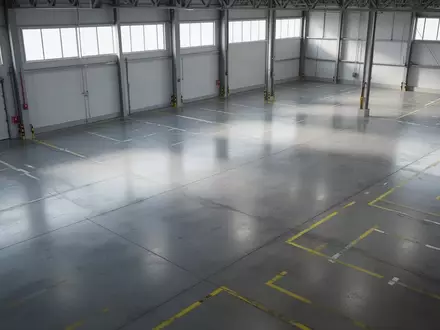 Leere, aufgeräumte Logistikhalle mit Industrieboden und Bodenmarkierungen in einer sachlichen, architektonischen Aufnahme. - Foto: über boerse-global.de