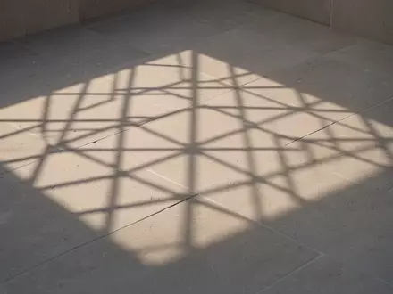 Ein abstraktes, geometrisches Rastermuster auf einer neutralen Steinoberfläche bei sanftem Morgenlicht. - Foto: über boerse-global.de