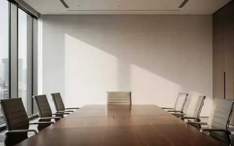 Ein minimalistischer, lichtdurchfluteter Konferenzraum mit einem leeren Holztisch und einer klaren architektonischen Struktur. - Foto: über boerse-global.de