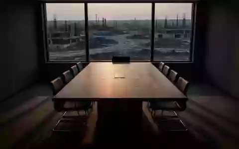 Ein leerer Konferenztisch in einem schattigen Raum vor dem Hintergrund einer unbesetzten Baustelle bei DĂ€mmerung. - Foto: ĂŒber boerse-global.de