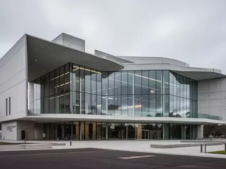 Ein modernes Regierungsgebäude aus Glas und Beton unter bewölktem Himmel in Canberra. - Foto: über boerse-global.de