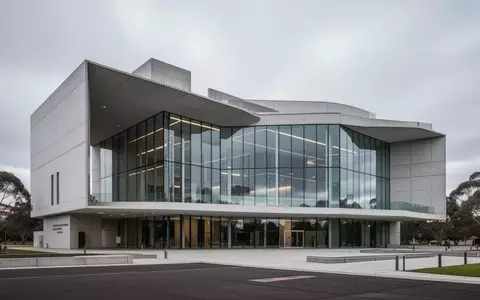 Ein modernes Regierungsgebäude aus Glas und Beton unter bewölktem Himmel in Canberra. - Foto: über boerse-global.de