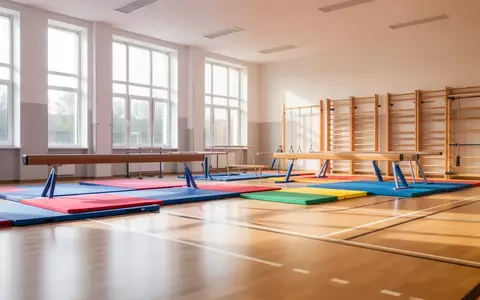 Heller, leerer Schulturnraum mit Sportgeräten und Bodenmatten in einem modernen Schulgebäude. - Foto: über boerse-global.de