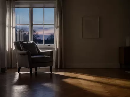 Ein ruhiges, spärlich beleuchtetes Wohnzimmer in der Abenddämmerung mit einem Sessel am Fenster. - Foto: über boerse-global.de