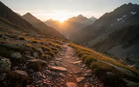 Ein sonnenbeschienener Bergpfad in einer alpinen Hochgebirgslandschaft bei Sonnenaufgang. - Foto: über boerse-global.de