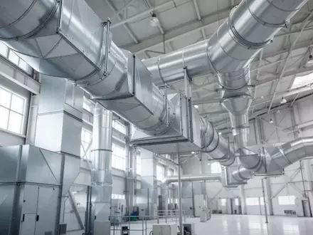 Ein modernes industrielles Lüftungssystem mit metallischen Filterrohren in einer hellen Produktionshalle. - Foto: über boerse-global.de