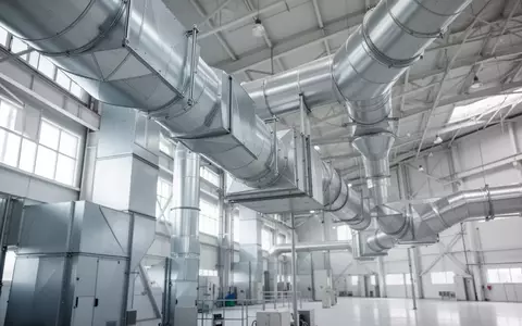 Ein modernes industrielles Lüftungssystem mit metallischen Filterrohren in einer hellen Produktionshalle. - Foto: über boerse-global.de