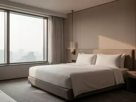 Ein minimalistisch eingerichtetes, leeres Hotelzimmer mit ordentlich gemachtem Bett und hellem Tageslichteinfall. - Foto: über boerse-global.de