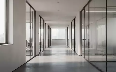 Ein heller, minimalistischer Büroflur mit Glaswänden und poliertem Betonboden in einer ruhigen, menschenleeren Umgebung. - Foto: über boerse-global.de
