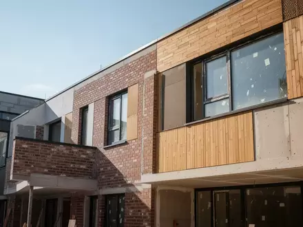 Ein renoviertes Wohngebäude mit moderner Fassade bei Tageslicht. - Foto: über boerse-global.de