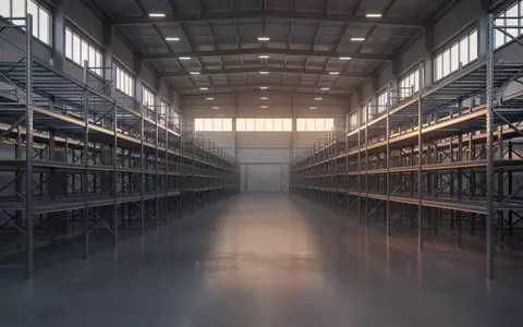 Ein weitläufiges, modernes Logistiklager mit leeren Metallregalen in einer sauberen Industriehalle bei natürlichem Licht. - Foto: über boerse-global.de