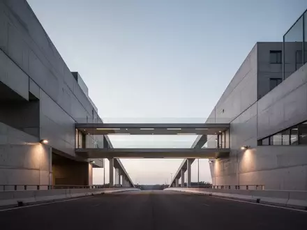 Minimalistische Architektur mit zwei durch eine Brücke verbundenen Gebäuden in der Abenddämmerung. - Foto: über boerse-global.de