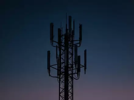 Ein Funkturm vor einem tiefblauen Dämmerungshimmel, der die technische Infrastruktur für Mobilfunk darstellt. - Foto: über boerse-global.de