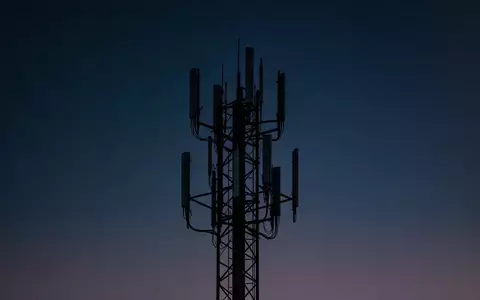 Ein Funkturm vor einem tiefblauen Dämmerungshimmel, der die technische Infrastruktur für Mobilfunk darstellt. - Foto: über boerse-global.de