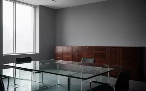 Ein minimalistisches, leeres Büro mit einem gläsernen Besprechungstisch und hölzernen Aktenschränken im Hintergrund. - Foto: über boerse-global.de