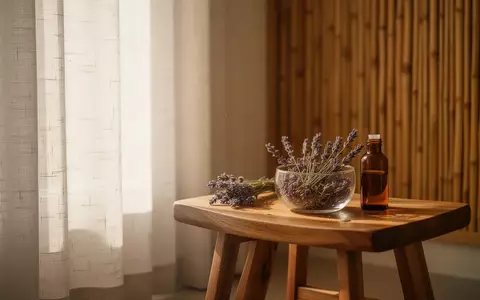 Ein minimalistischer Wellnessraum mit Sonnenlicht, Lavendelblüten in einer Schale und einer kleinen Glasflasche. - Foto: über boerse-global.de