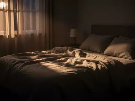 Ein ruhiges, abgedunkeltes Schlafzimmer bei Nacht mit sanftem Mondlicht, das auf ein ungemachtes Bett fĂ€llt. - Foto: ĂŒber boerse-global.de