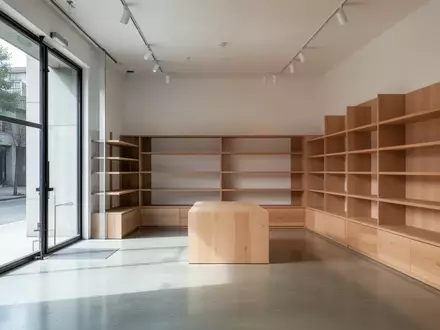 Ein minimalistisch gestalteter, leerer Verkaufsraum mit Holzregalen und Betonboden bei natürlichem Tageslicht. - Foto: über boerse-global.de