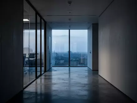 Ein minimalistischer, ruhiger Büroflur in der Dämmerung mit weichem Lichteinfall und klaren architektonischen Linien. - Foto: über boerse-global.de