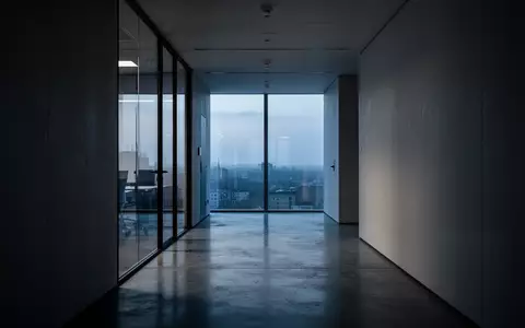 Ein minimalistischer, ruhiger Büroflur in der Dämmerung mit weichem Lichteinfall und klaren architektonischen Linien. - Foto: über boerse-global.de