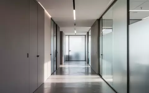 Ein minimalistischer, moderner Büroflur mit klaren Linien und indirektem Tageslicht, der eine professionelle und sichere Umgebung symbolisiert. - Foto: über boerse-global.de