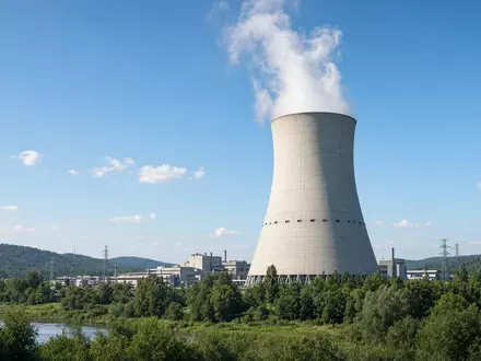 Ein modernes Kernkraftwerk mit KĂĽhlturm vor einem klaren blauen Himmel. - Foto: ĂĽber boerse-global.de