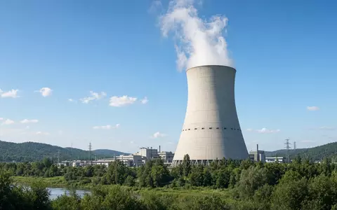 Ein modernes Kernkraftwerk mit Kühlturm vor einem klaren blauen Himmel. - Foto: über boerse-global.de