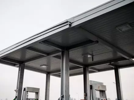 Moderne, minimalistische Überdachung einer Tankstelle unter einem bewölkten Himmel ohne jegliche Beschriftung oder Fahrzeuge. - Foto: über boerse-global.de