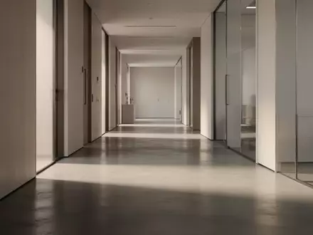 Ein heller, leerer Flur mit minimalistischer Architektur und klaren Schattenwürfen auf einem Betonboden. - Foto: über boerse-global.de