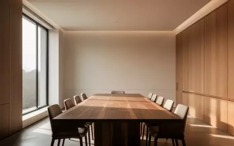 Ein minimalistischer, moderner Konferenzraum mit natürlichem Lichteinfall und einer leeren, polierten Holztischplatte. - Foto: über boerse-global.de