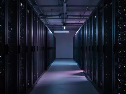 Dunkler Serverraum mit beleuchteten Racks und abstrakten Lichtreflexen als Symbol für digitale Bedrohungen. - Foto: über boerse-global.de