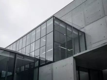Moderne Glas- und Betonfassade eines Bürogebäudes bei bewölktem Himmel. - Foto: über boerse-global.de