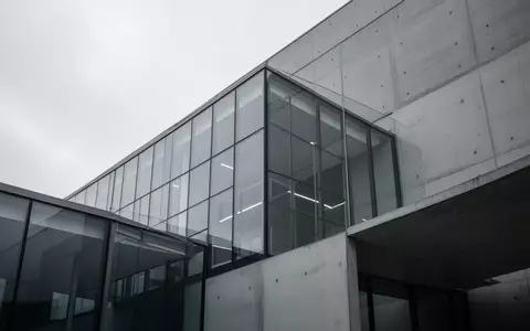 Moderne Glas- und Betonfassade eines Bürogebäudes bei bewölktem Himmel. - Foto: über boerse-global.de