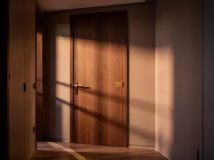 Ein schmaler, in dämmriges Licht getauchter Flur in einer Wohnung mit einer geschlossenen Zimmertür und langen Schatten. - Foto: über boerse-global.de