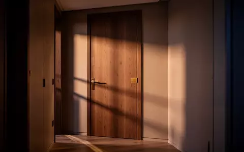 Ein schmaler, in dämmriges Licht getauchter Flur in einer Wohnung mit einer geschlossenen Zimmertür und langen Schatten. - Foto: über boerse-global.de