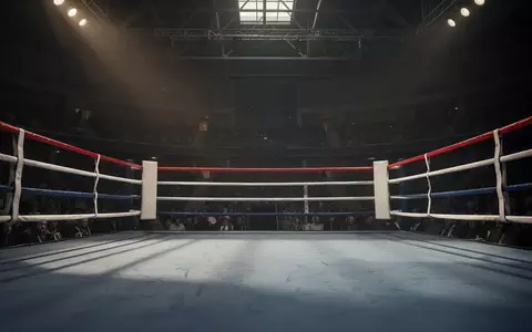 Ein leerer Boxring in einer abgedunkelten Arena mit natürlichem Lichteinfall auf den Boden. - Foto: über boerse-global.de