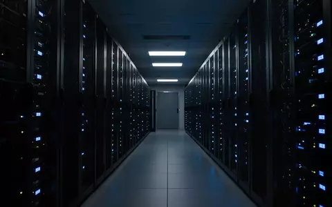 Dunkler, moderner Serverraum mit Reihen von technischen Geräten und blauen Statusleuchten. - Foto: über boerse-global.de