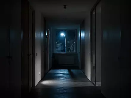 Ein dunkler, minimalistischer Flur bei Nacht mit kühlem Lichteinfall durch ein Fenster. - Foto: über boerse-global.de