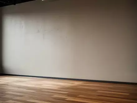Ein minimalistischer, leerer Fitnessraum mit einer schlichten Wand und Holzboden in natürlichem Tageslicht. - Foto: über boerse-global.de