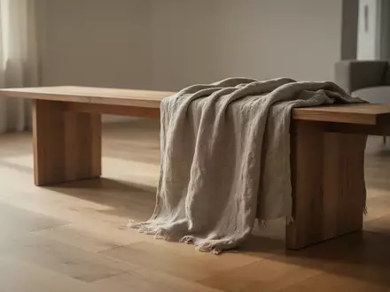 Ein minimalistisch eingerichteter Raum mit weichem Tageslicht, einer schlichten Holzbank und einem strukturierten Textil. - Foto: über boerse-global.de