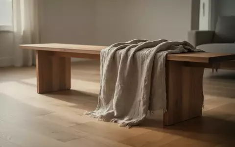 Ein minimalistisch eingerichteter Raum mit weichem Tageslicht, einer schlichten Holzbank und einem strukturierten Textil. - Foto: über boerse-global.de