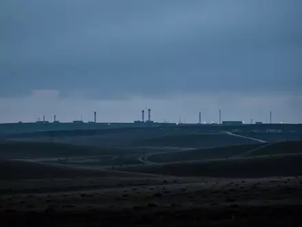 Eine weitläufige, einsame Landschaft nahe einer militärischen Einrichtung in der Dämmerung, die Ruhe und Schwere ausstrahlt. - Foto: über boerse-global.de