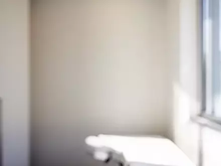 Ein minimalistischer, heller Untersuchungsraum in einer modernen Praxis mit sanftem Tageslicht und neutraler Atmosphäre. - Foto: über boerse-global.de