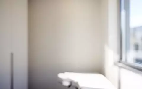 Ein minimalistischer, heller Untersuchungsraum in einer modernen Praxis mit sanftem Tageslicht und neutraler Atmosphäre. - Foto: über boerse-global.de