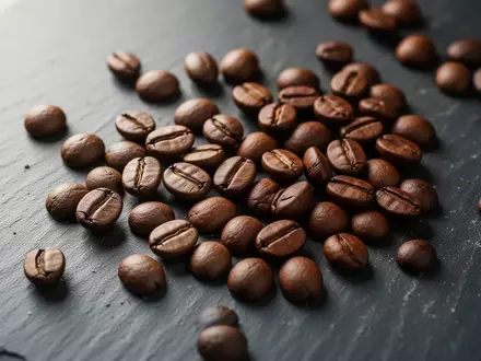 Nahaufnahme von gerösteten Kaffeebohnen auf einer dunklen Schieferoberfläche. - Foto: über boerse-global.de