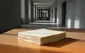 Ein Stapel leerer Dokumente auf einem schlichten Holztisch in einem ruhigen, modernen Büroflur. - Foto: über boerse-global.de