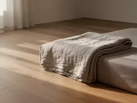Ein minimalistisch eingerichteter, ruhiger Raum mit einer gefalteten Decke in sanftem Tageslicht. - Foto: über boerse-global.de