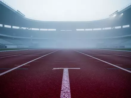 Leere Laufbahn auf einer Sportanlage bei Dämmerung und leichtem Nebel - Foto: über boerse-global.de